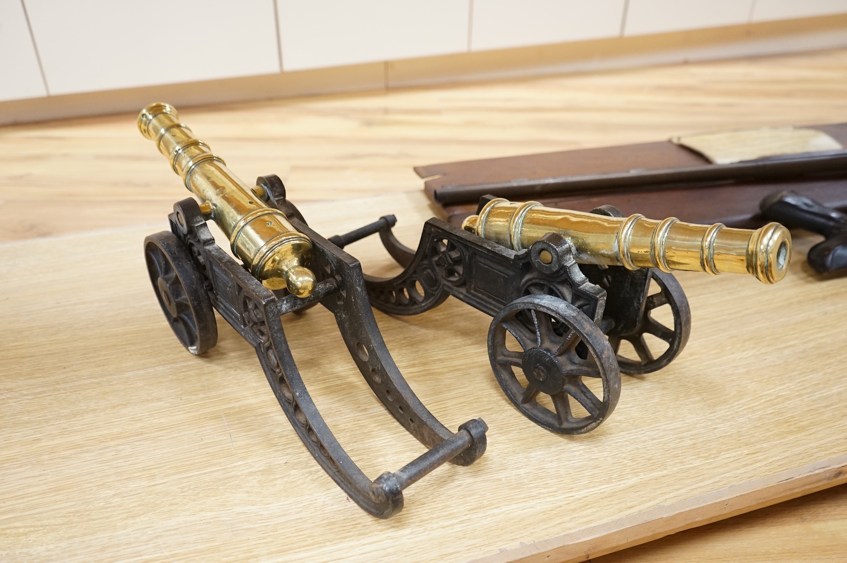 A decorative pair of brass model cannons, with turned barrels, 29cm overall, on cast iron pierced carriages with pierced wheels, overall length 46cm